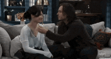 a man and a woman are sitting on a couch and the man is touching the woman 's neck .