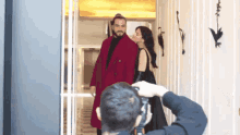 a man is taking a picture of a woman in a red coat