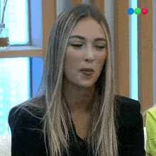 a woman with long blonde hair is sitting on a couch and making a face