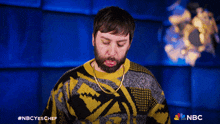 a man with a beard is wearing a sweater that says nbc on the front