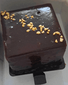 a square chocolate cake with nuts on top is in a box