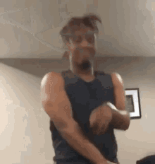 a man in a black tank top is standing in a room .