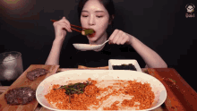 a woman is eating noodles with chopsticks from a plate