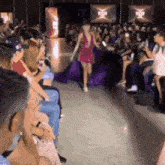 a woman in a purple dress is walking down a runway .