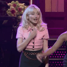 a woman in a pink crop top and black skirt is dancing
