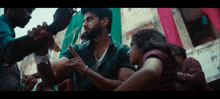 a man in a green shirt is pointing at a woman in a crowd