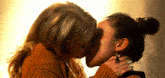 two women are kissing each other in a room .