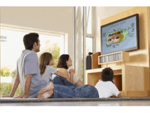 a family sits on the floor watching a television showing puerto rico