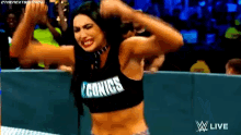 a woman in a wrestling ring wearing a black top that says iconics on it