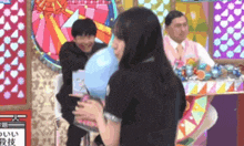 a woman is holding a cotton candy balloon in front of a man .