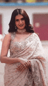 a woman wearing a white saree and a choker stands in front of a building