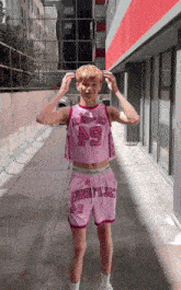 a young man wearing a pink crop top with the number 45 on it