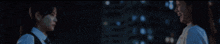 two women are standing next to each other in the dark .