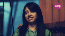 a woman in a green polka dot shirt is smiling in front of a pink zing logo