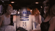 a group of women standing around a r2d2 robot .