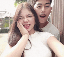 a man and a woman are posing for a picture and the woman has her tongue out