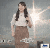 a woman in a plaid skirt is standing in front of a sign that says deicy on it