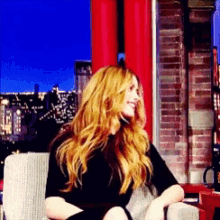 a woman with red hair is sitting in a chair