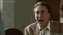 a man in a suit and tie is making a funny face while talking to another man .