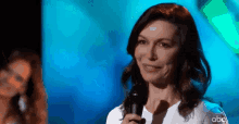 a woman is smiling while holding a microphone on a stage