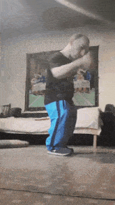 a man in a black shirt and blue pants dancing in front of a painting