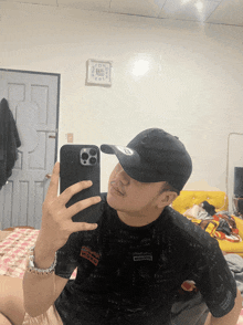 a man is taking a picture of himself in a mirror while wearing a hat and a shirt that says momo on it
