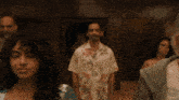 a man in a hawaiian shirt is standing in a room with other people