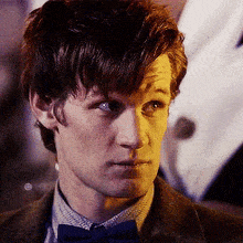 a close up of a man wearing a suit and a blue bow tie