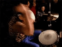 a man is sitting on the floor playing drums in front of a crowd of people .