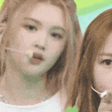two women are standing next to each other and one is holding a lollipop in her mouth .