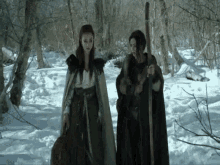 two women standing in the snow holding sticks and a bag