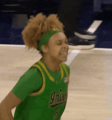 a female basketball player wearing a green jersey that says irish on it