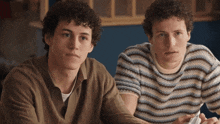 two men with curly hair wearing striped sweaters