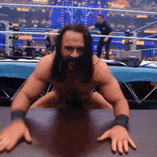 a shirtless wrestler is kneeling on a table in front of a sign that says ' smackdown ' on it