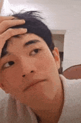 a young man is holding his hand to his forehead and making a funny face .