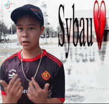 a young boy stands in front of a sign that says sybau on it