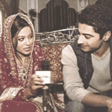 a man and a woman are sitting next to each other talking into a microphone .