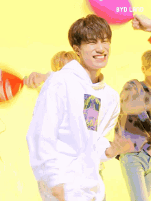a boy wearing a white hoodie making a heart sign with his hand