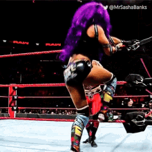 a female wrestler with purple hair is standing in a wrestling ring .