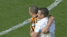 two men on a soccer field one wearing a yellow and black striped shirt that says karoo
