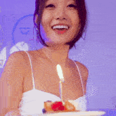 a woman in a white tank top is smiling with a lit candle in her chest