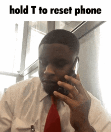 a man in a white shirt and red tie talking on a cell phone with the words hold t to reset phone above him