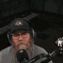 a man with a beard wearing headphones and a hat is playing a video game .