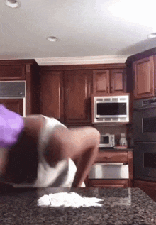 a person standing on a counter in a kitchen with a microwave oven