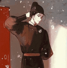 a man in a black costume is standing in front of a red door holding his hat .