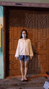 a woman wearing a mask stands in front of a door