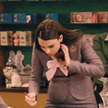 a woman in a gray suit with a pink bow has a badge on her jacket that says festina