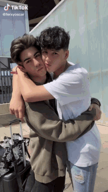two young men hugging each other in front of a building with a tik tok watermark