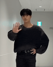 a man wearing a black sweater and black pants is waving