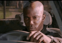 a man is sitting in the driver 's seat of a car looking at his watch .